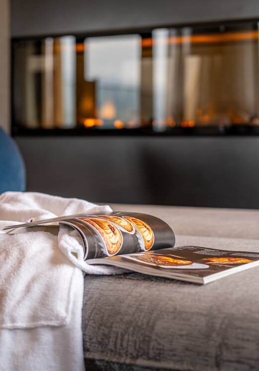 Gemütliche Liege mit Bademantel, Magazin und Kamin