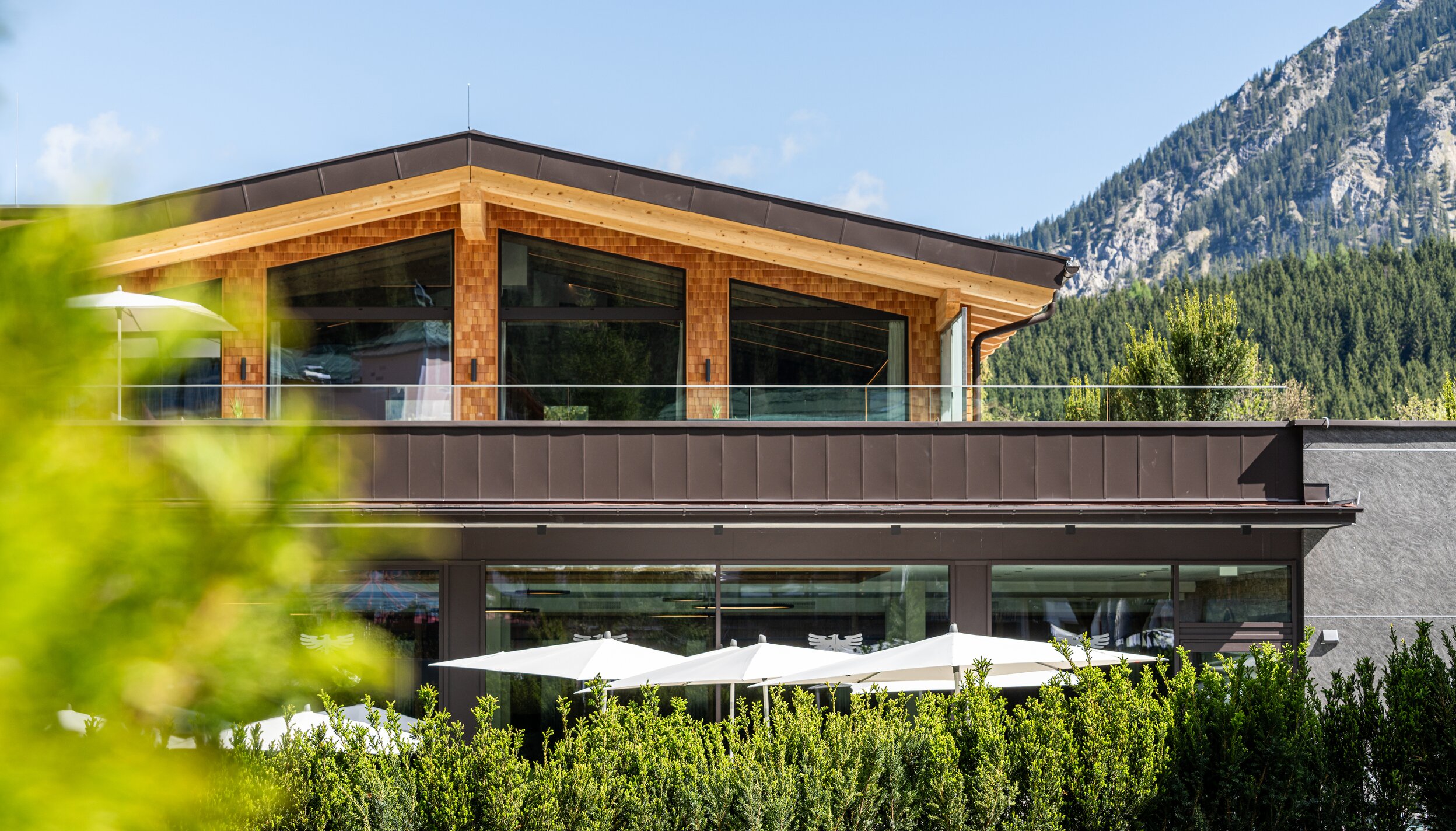 Hotel Tyrol am Haldensee, Außenansicht mit Terrasse und Sonnenschirmen