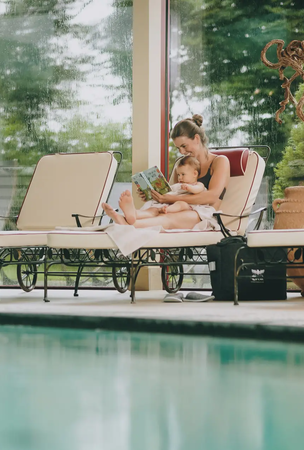 Mutter liest Kind am Hotelpool vor