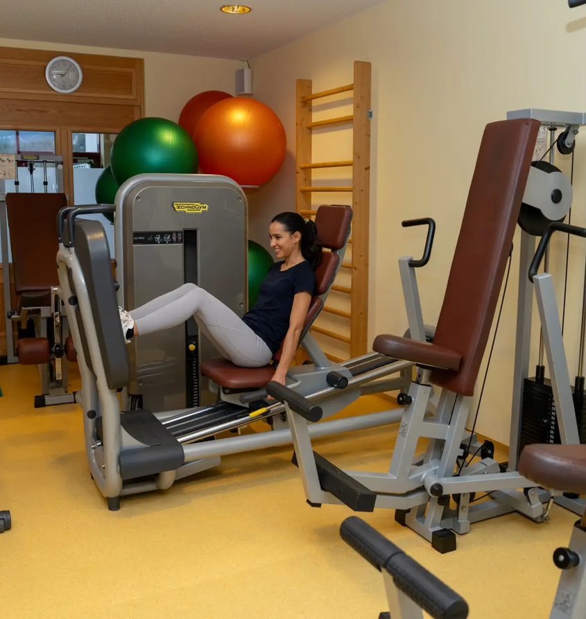 Frau trainiert an Beinpresse im Fitnessraum