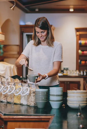 Frau schöpft Müsli am Frühstücksbuffet im Hotel Tyrol Haldensee