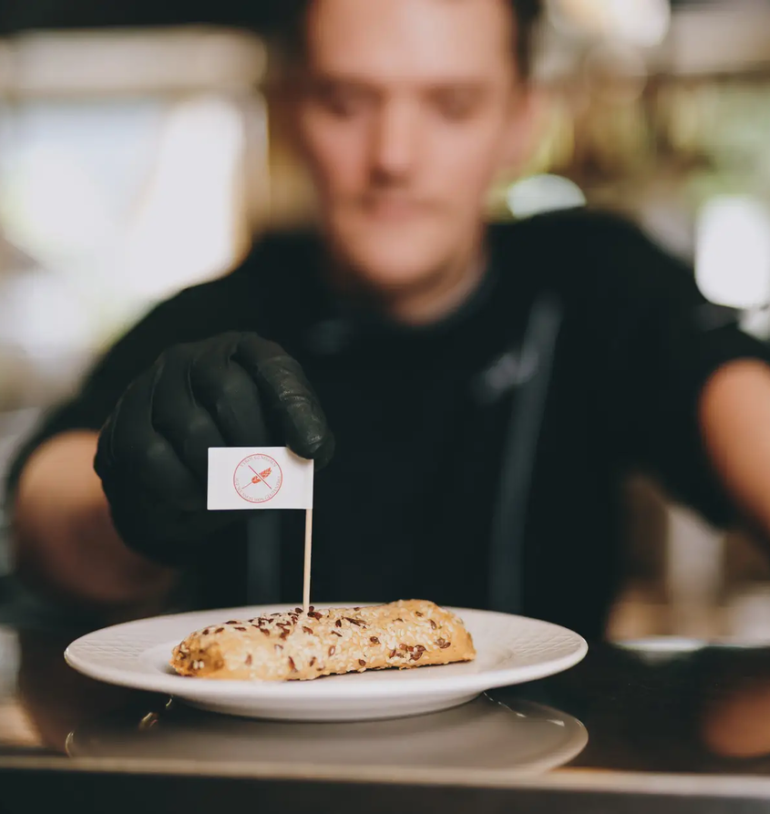 Koch präsentiert Gebäck mit Fähnchen im Hotel Tyrol