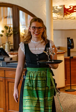 Kellnerin im Dirndl mit Tablett im Hotel Tyrol