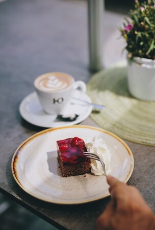 Kuchenstück mit Sahne, Kaffee und Blume im Hotel Tyrol Haldensee