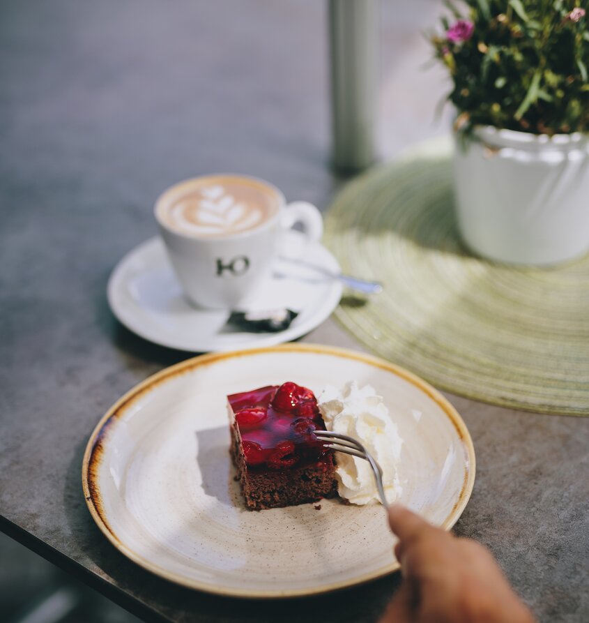 Kuchenstück mit Sahne, Kaffee und Blume im Hotel Tyrol Haldensee