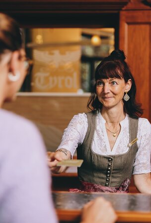 Hotel Tyrol Rezeptionistin gibt Gast Karte