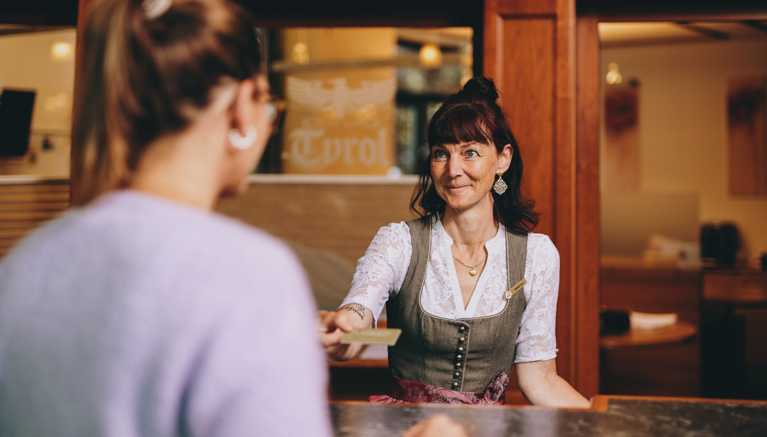 Hotel Tyrol Rezeptionistin gibt Gast Karte