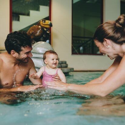 Glückliche Familie mit Baby beim Planschen im Hotelpool