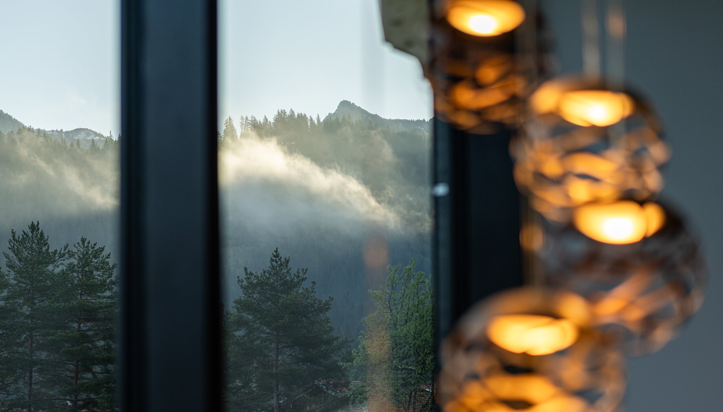 Fensterblick auf nebelverhangene Berglandschaft mit Bäumen