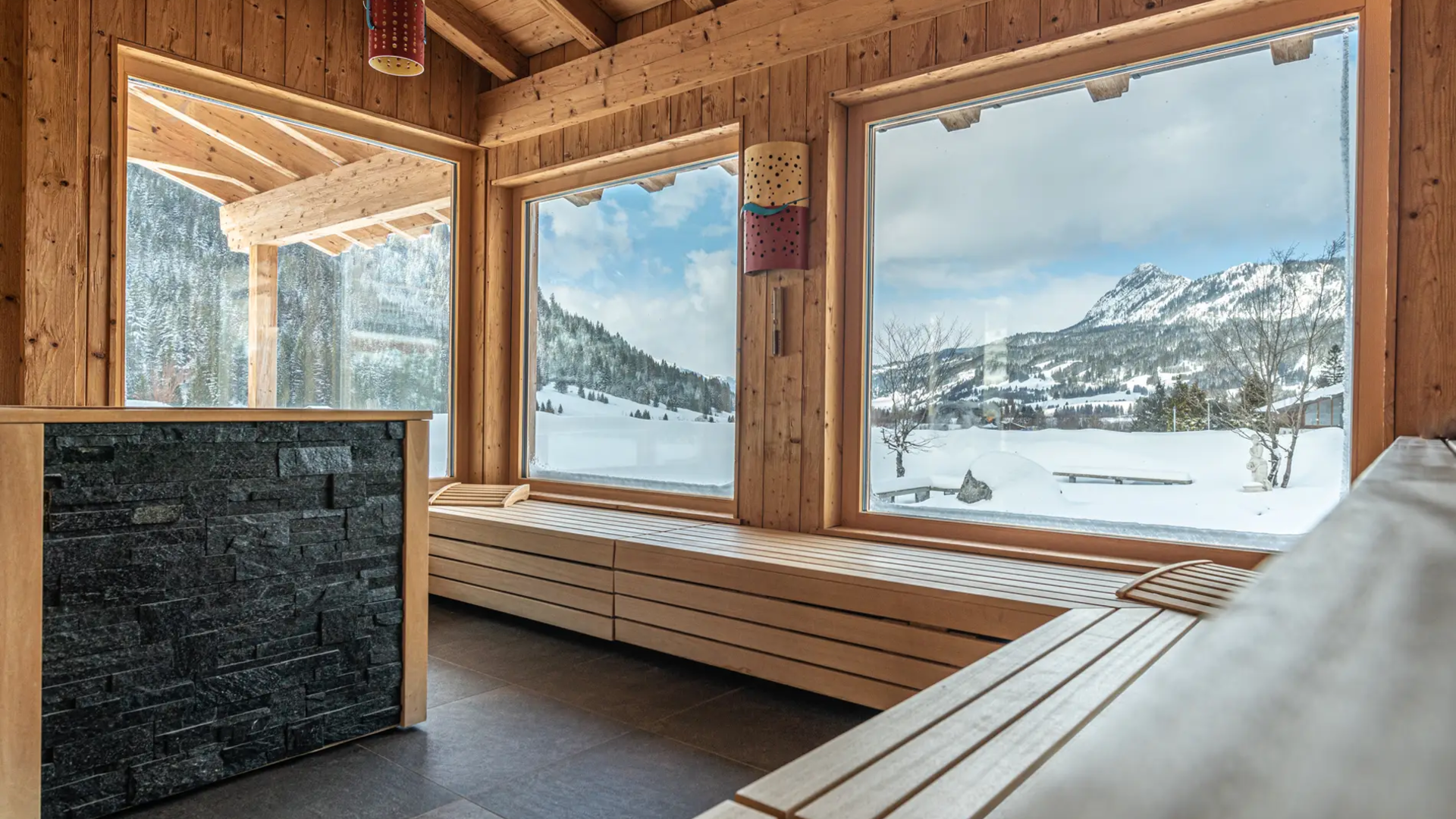 Holzsauna mit Blick auf verschneite Berge im Hotel Tyrol am Haldensee