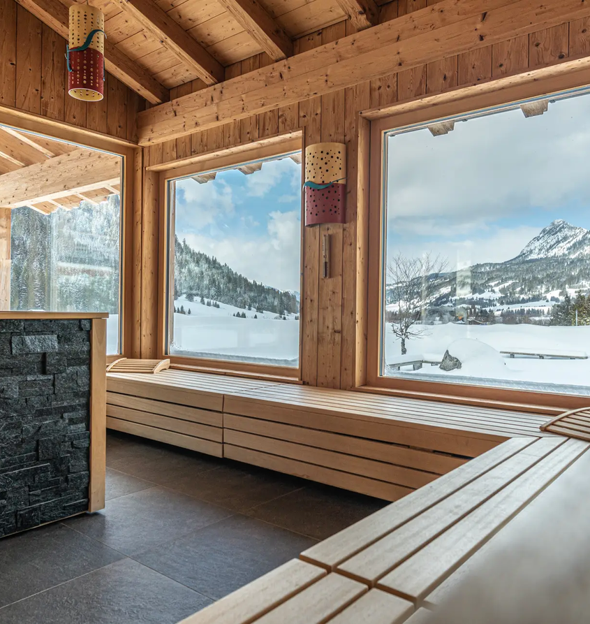 Holzsauna mit Blick auf verschneite Berge im Hotel Tyrol am Haldensee