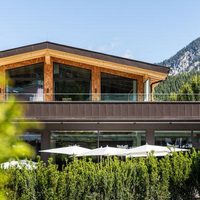 Hotel Tyrol am Haldensee, Außenansicht mit Terrasse und Berg im Hintergrund
