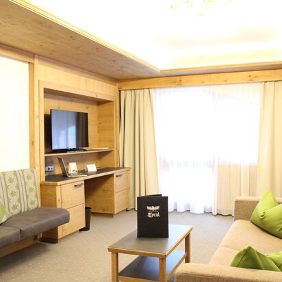 Hotelzimmer mit Sofa, Tisch, Schreibtisch und Fernseher