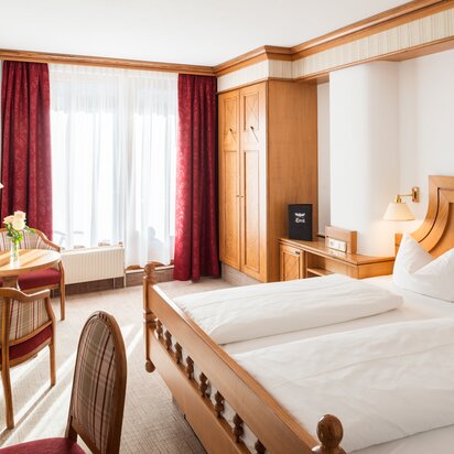 Hotelzimmer mit Doppelbett, Schrank und rotem Vorhang