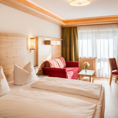 Hotel Tyrol Zimmer mit Bett, Sofa und Tisch