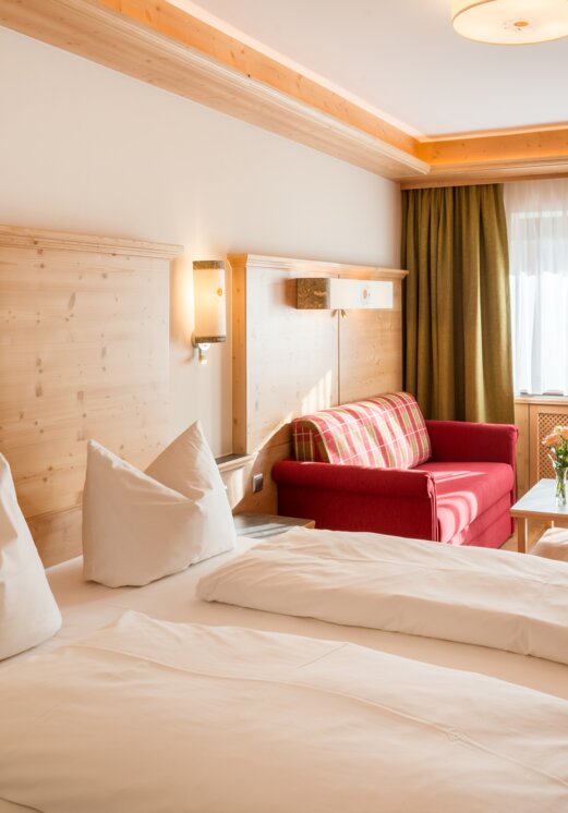 Hotel Tyrol Zimmer mit Bett, Sofa und Tisch