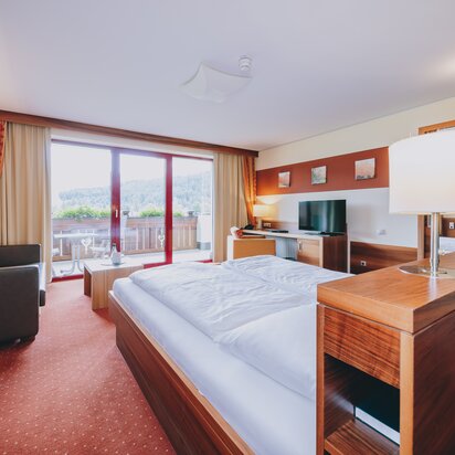 Hotelzimmer mit Doppelbett und Balkon im Hotel Tyrol am Haldensee