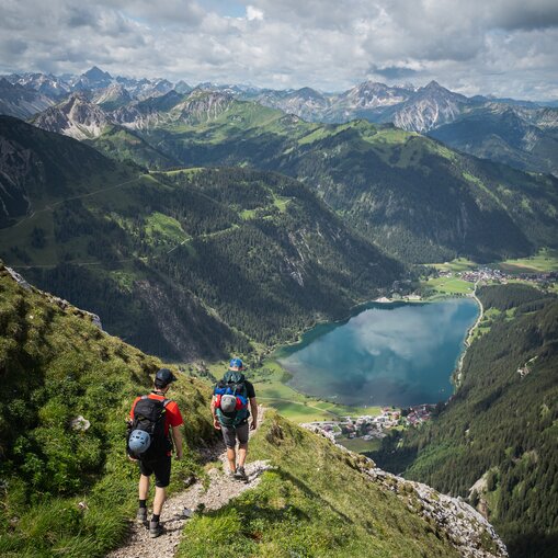 Wanderer blicken auf Haldensee und Berglandschaft