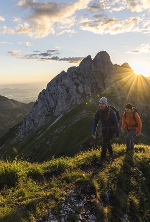 Zwei Wanderer bei Sonnenaufgang in den Bergen