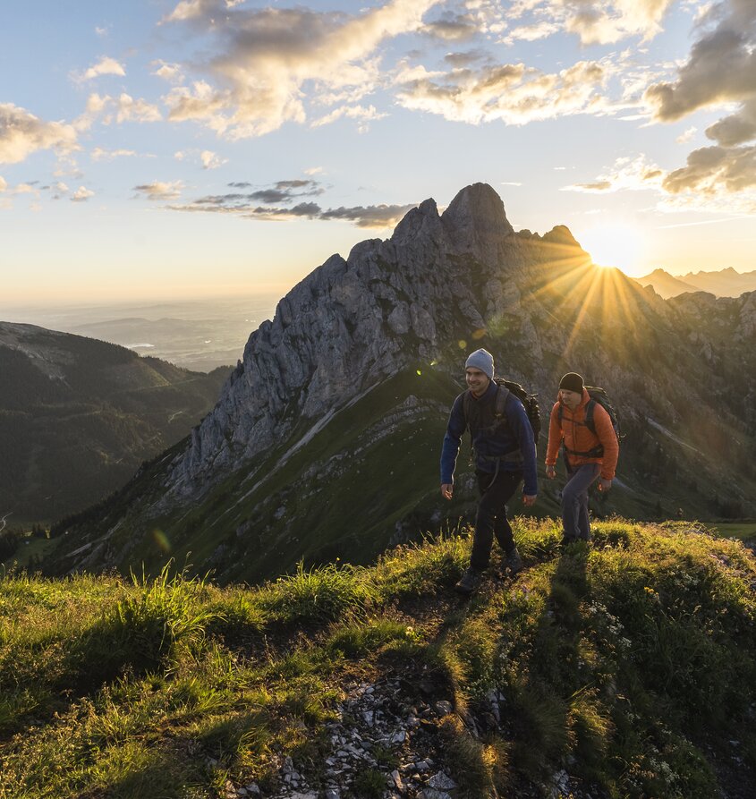 Zwei Wanderer bei Sonnenaufgang in den Bergen