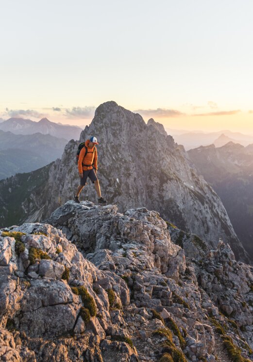 Wanderer auf felsigem Berggipfel bei Sonnenaufgang