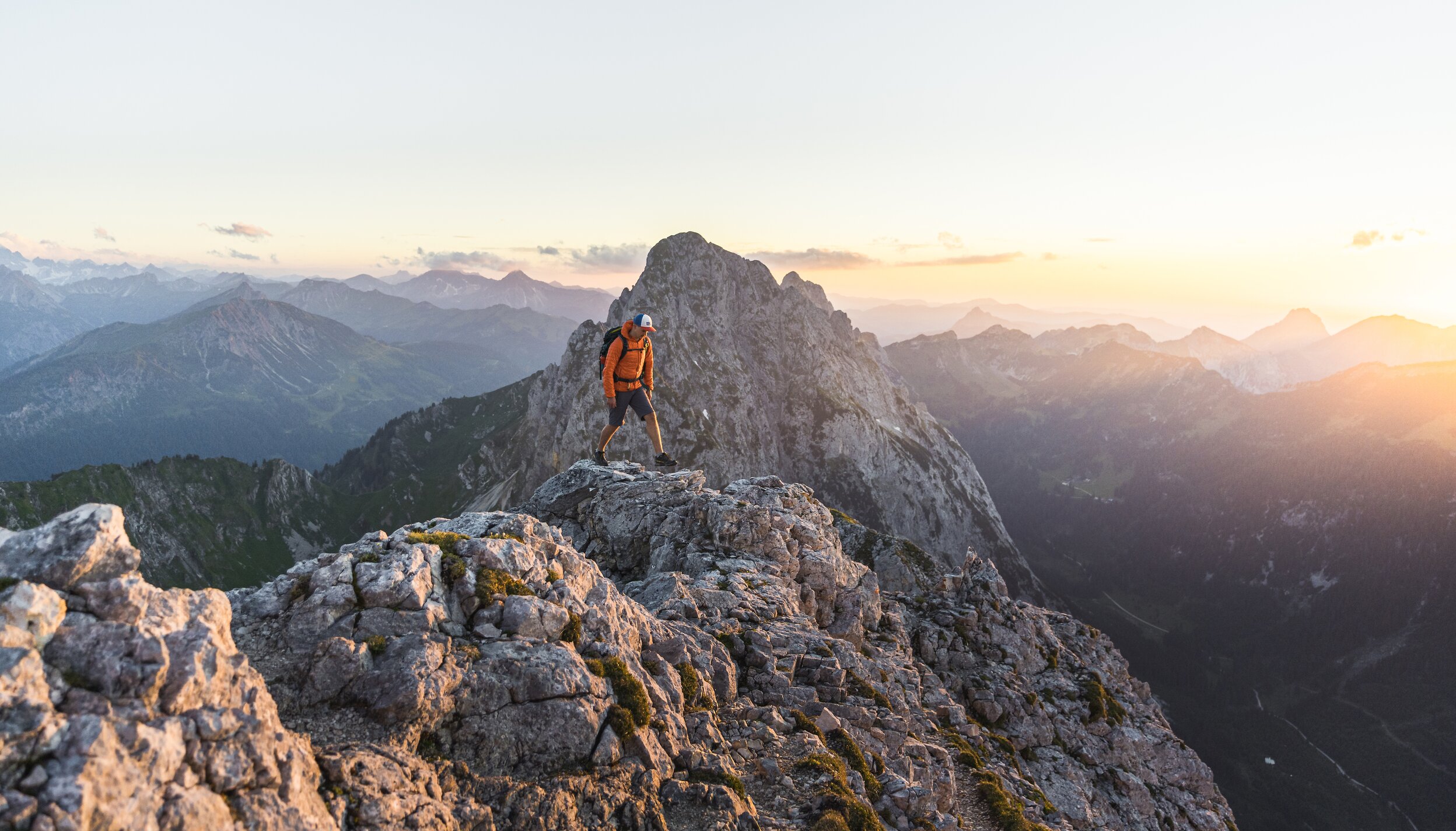 Wanderer auf felsigem Berggipfel bei Sonnenaufgang