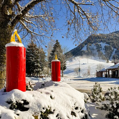 Winterlandschaft mit roten Kerzen vor Bergkulisse