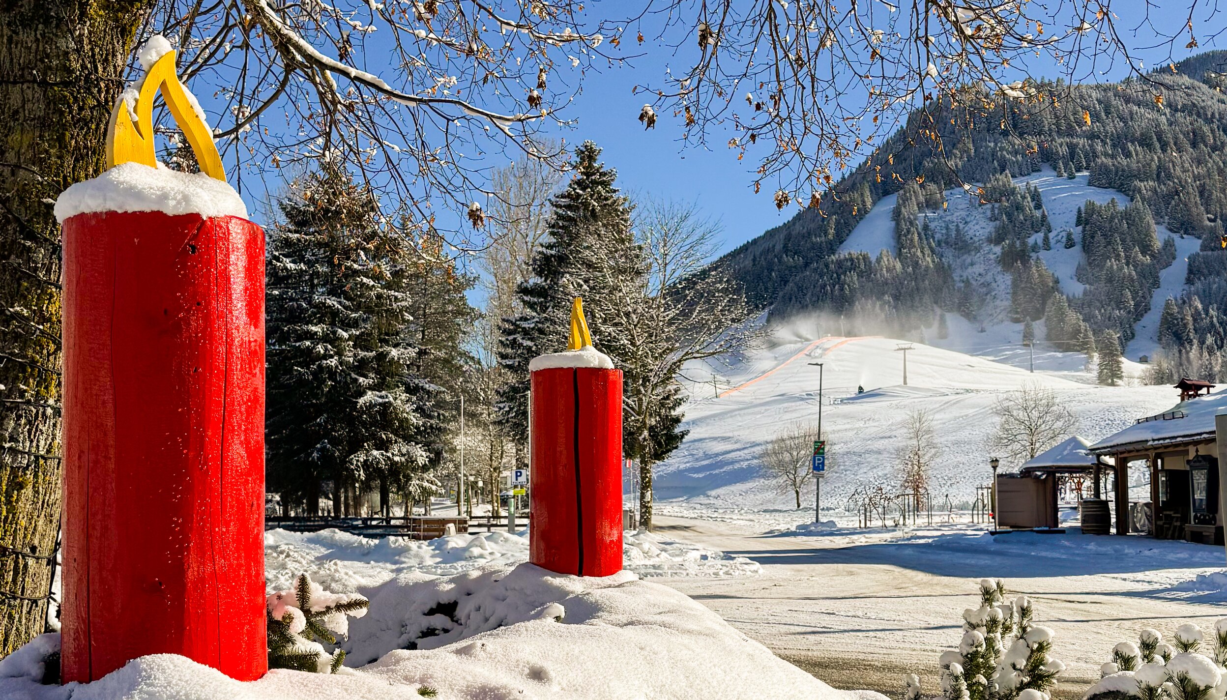 Winterlandschaft mit roten Kerzen vor Bergkulisse