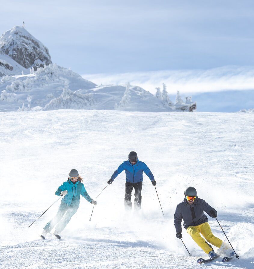 Skifahrer im Schnee vor verschneiter Berglandschaft