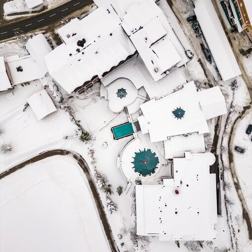 Winterliche Luftaufnahme des schneebedeckten Hotel Tyrol mit Pool